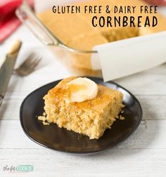 a piece of cornbread on a black plate next to a glass baking dish and knife