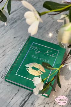 a green book with white flowers on it and the words mr eal planner next to it