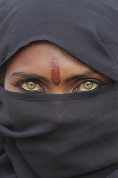 a woman with green eyes wearing a black hijab