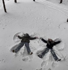 two people are laying in the snow with their arms spread out to form a heart