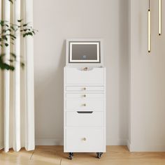 a white chest of drawers with a monitor on top