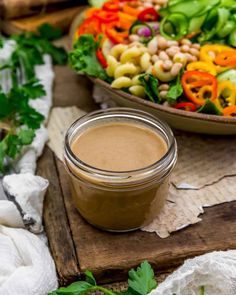 a bowl of salad with dressing next to it