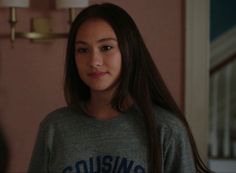 a young woman with long hair standing in a living room next to a wall light