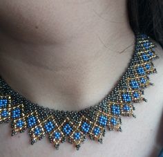 a woman wearing a blue and gold beaded necklace on her neck with an earring