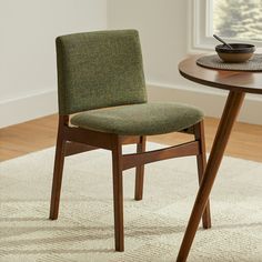 a green chair sitting next to a wooden table on top of a white carpeted floor