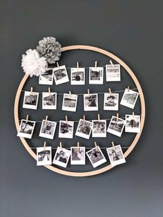 a wooden circle with pictures hanging on clothes pins and flowers in the middle, along with photos pinned to pegs