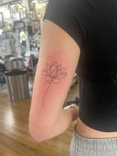 a woman's arm with a small flower tattoo on the back of her left arm