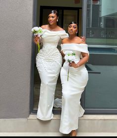 two women in white dresses standing next to each other