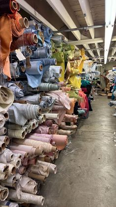 many different colored fabrics are on display in a store with lots of them hanging from the ceiling