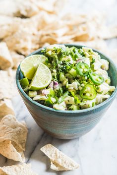 a blue bowl filled with vegetables and tortilla chips on top of a table