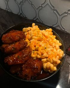 a plate full of macaroni and cheese with chicken wings