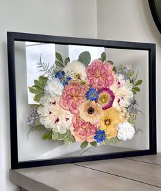 a vase filled with flowers sitting on top of a wooden table next to a mirror