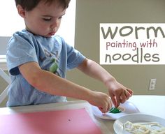 a little boy that is sitting at a table with some noodles in front of him