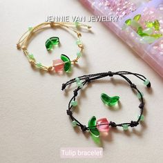 two bracelets with green and pink flowers on them next to a beaded box