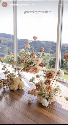 flowers are arranged in vases on a wooden table by the large windows with panoramic view