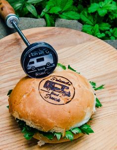 a burger on a wooden board with a grill in the middle and an air freshener attached to it