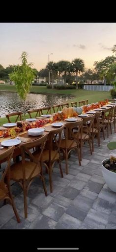 a long table set up with plates and bowls full of food for an outdoor event