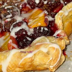 a pastry with white icing and fruit toppings sitting on top of parchment paper