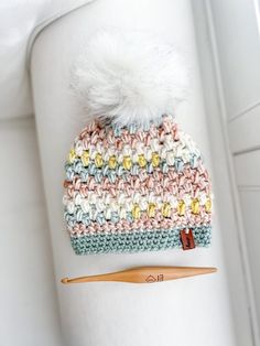 a crocheted hat with a white pom - pom sitting on top of it