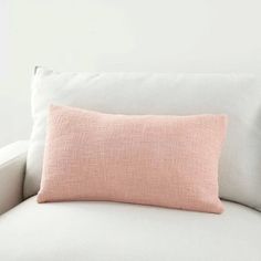 a pink pillow sitting on top of a white couch