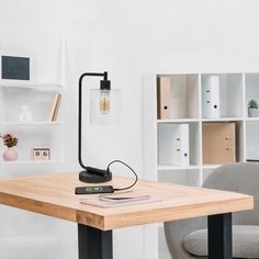 a wooden table with a lamp on top of it next to a chair and bookshelf