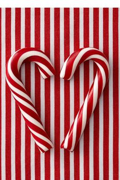 two candy canes in the shape of a heart on a red and white striped tablecloth