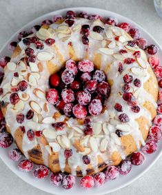 a white plate topped with a bundt cake covered in frosting and cranberries