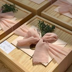 four wooden boxes with pink bows tied to them and some cards on the table next to each other