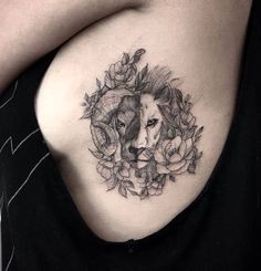 a woman with a lion tattoo on her shoulder and chest, holding flowers in front of her stomach