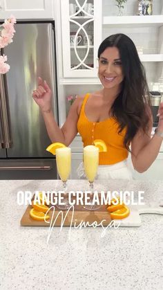 a woman standing in front of an orange creamsice drink on top of a counter