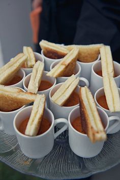 there are many small cups with sandwiches in them on the tray and one is filled with sauces