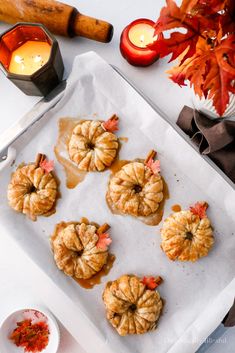 small pumpkins are on a baking sheet next to some candles and other autumn decorations