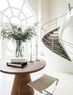 a table with a vase on it next to a spiral stair case and a chair