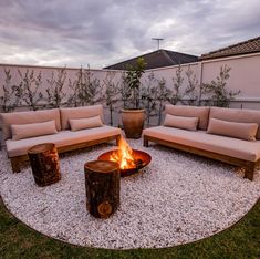 a fire pit surrounded by wooden furniture and gravel