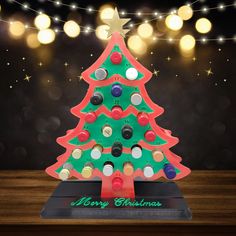 a wooden christmas tree with lights around it on top of a table in front of a dark background