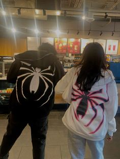 two people dressed up in costumes walking through a store aisle with one person wearing a spider man hoodie