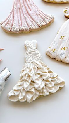 some cookies are decorated like dresses and seashells on a white table with scissors