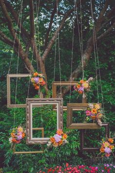 three frames are hanging from strings with flowers on them and one frame is suspended in the air