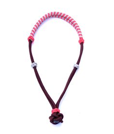 a red and white necklace with an orange knot on it's end, hanging from a brown cord