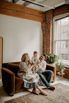 a man, woman and child sitting on a couch in front of a large window