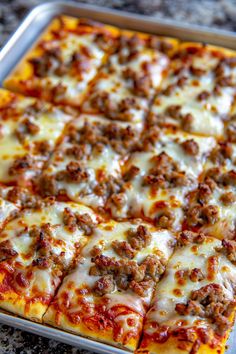 a square pizza sitting on top of a pan covered in cheese and meat toppings