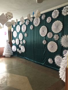 some paper snowflakes are hanging on the wall in front of a green curtain