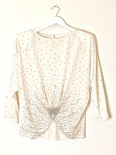 Gorgeous and unique silk cream blouse with gold glitter dots and a front asymmetrical silver sequin and Pearl beaded broach detail in the 1920s style  Super unique and one of a kind statement top  100% silk  Shoulder pads and keyhole button back enclosure  3/4 length sleeves Fits size S/M/L Vintage Martinique Fashion Cream Silk Blouse  Flapper style sequin beaded glitter star top perfect for New Years Eve! Sparkly Blouse, Cream Silk Blouse, Cream Blouse, Flapper Style, Cream Silk, Star Top, 1920s Fashion, Sequin Beading, Party Tops