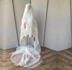 a mannequin is covered with white fabric on a wooden floor in front of a wall