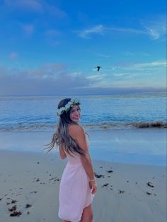 a woman standing on top of a beach next to the ocean