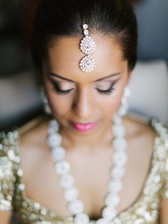 a woman in a gold dress with pearls on her head wearing a necklace and earrings