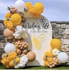 balloons and flowers decorate the entrance to a bee - themed birthday party