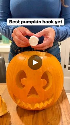 a woman is carving a jack - o'- lantern pumpkin with her thumb on it