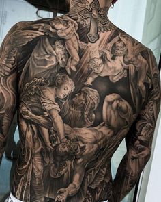 the back of a man's body with tattoos on it, including an image of jesus