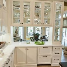 a kitchen with white cabinets and glass doors